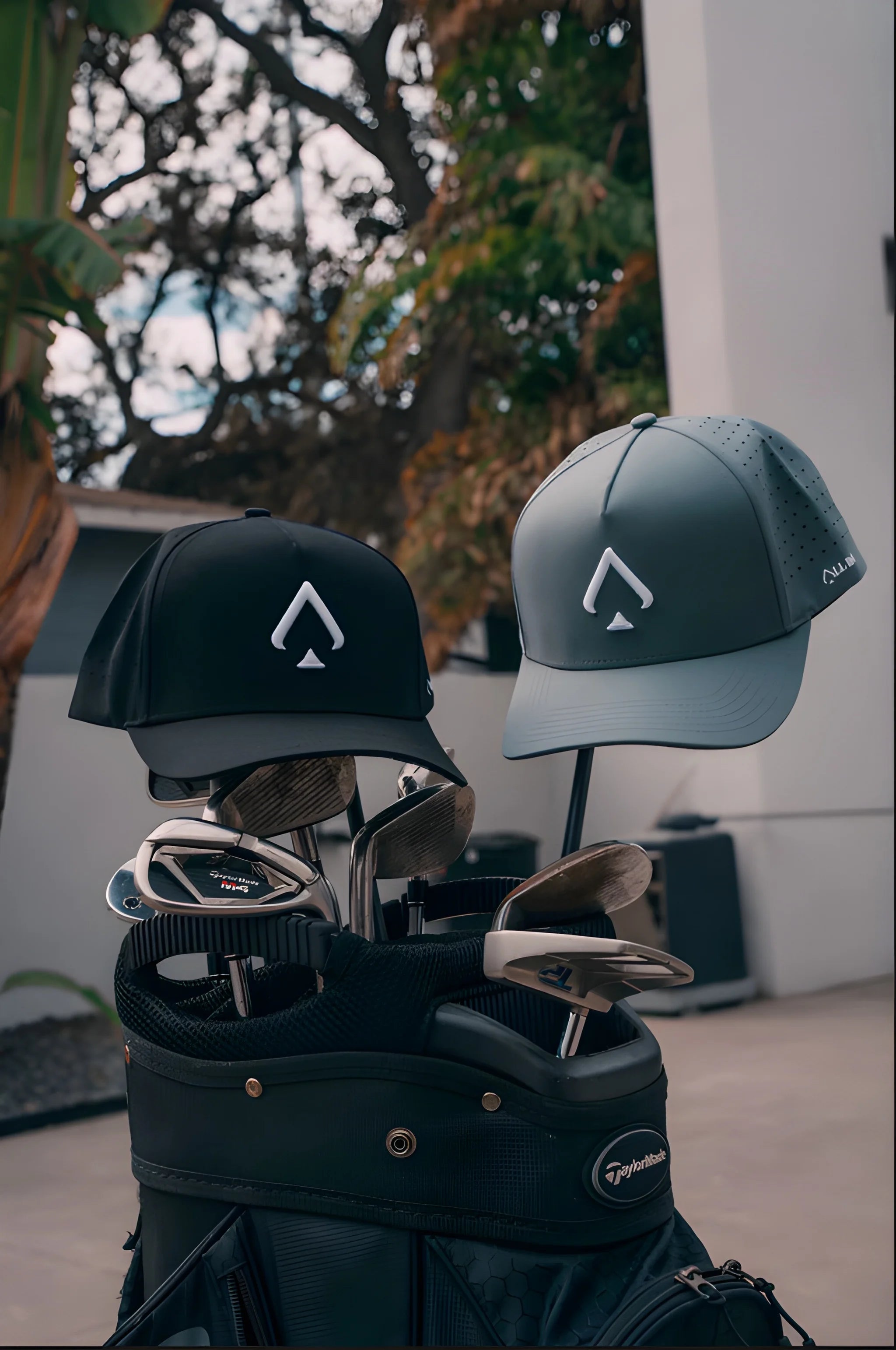 Two golf caps on a golf bag with trees in the background