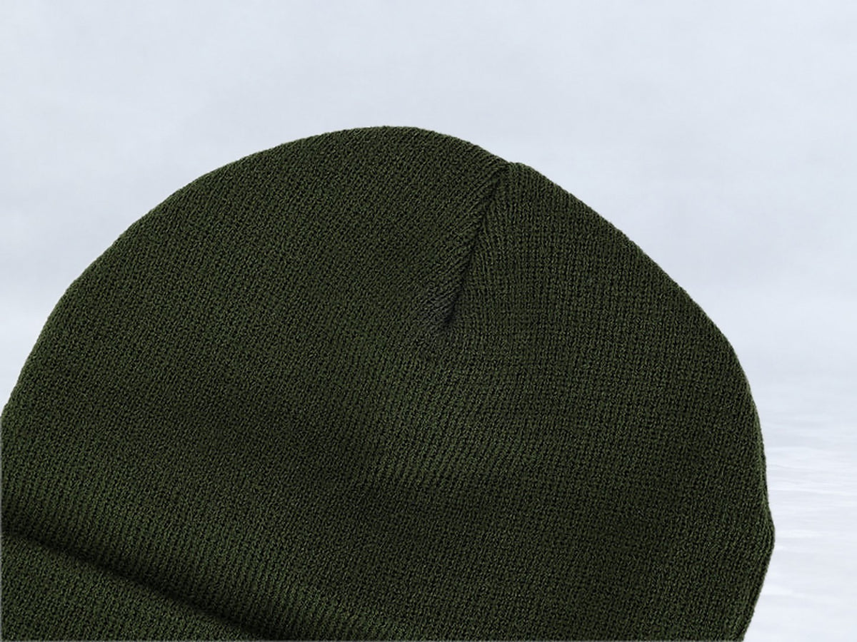 All In Lid Forest Green cuffed beanie in forest green knit, close-up of the knit crown, against a pale gray studio background.