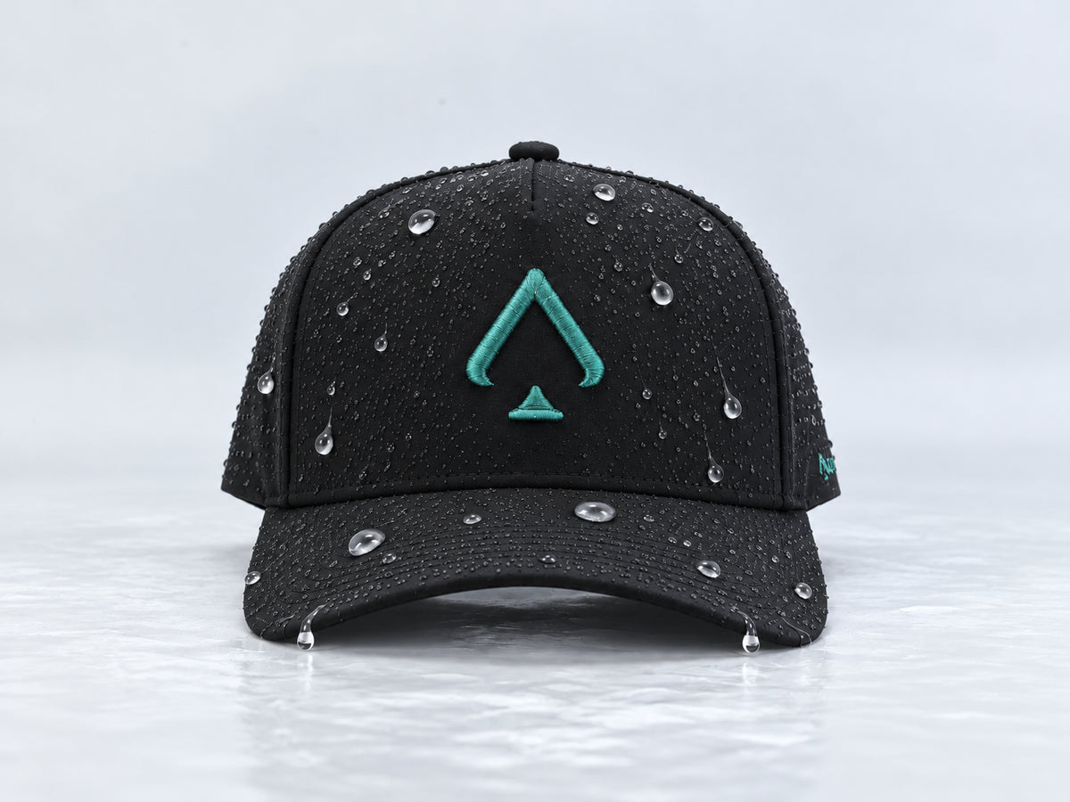 All In Lid Green Goblin black cap with teal green spade embroidery and beaded water droplets on the crown and brim, straight-on front view against a pale gray background.