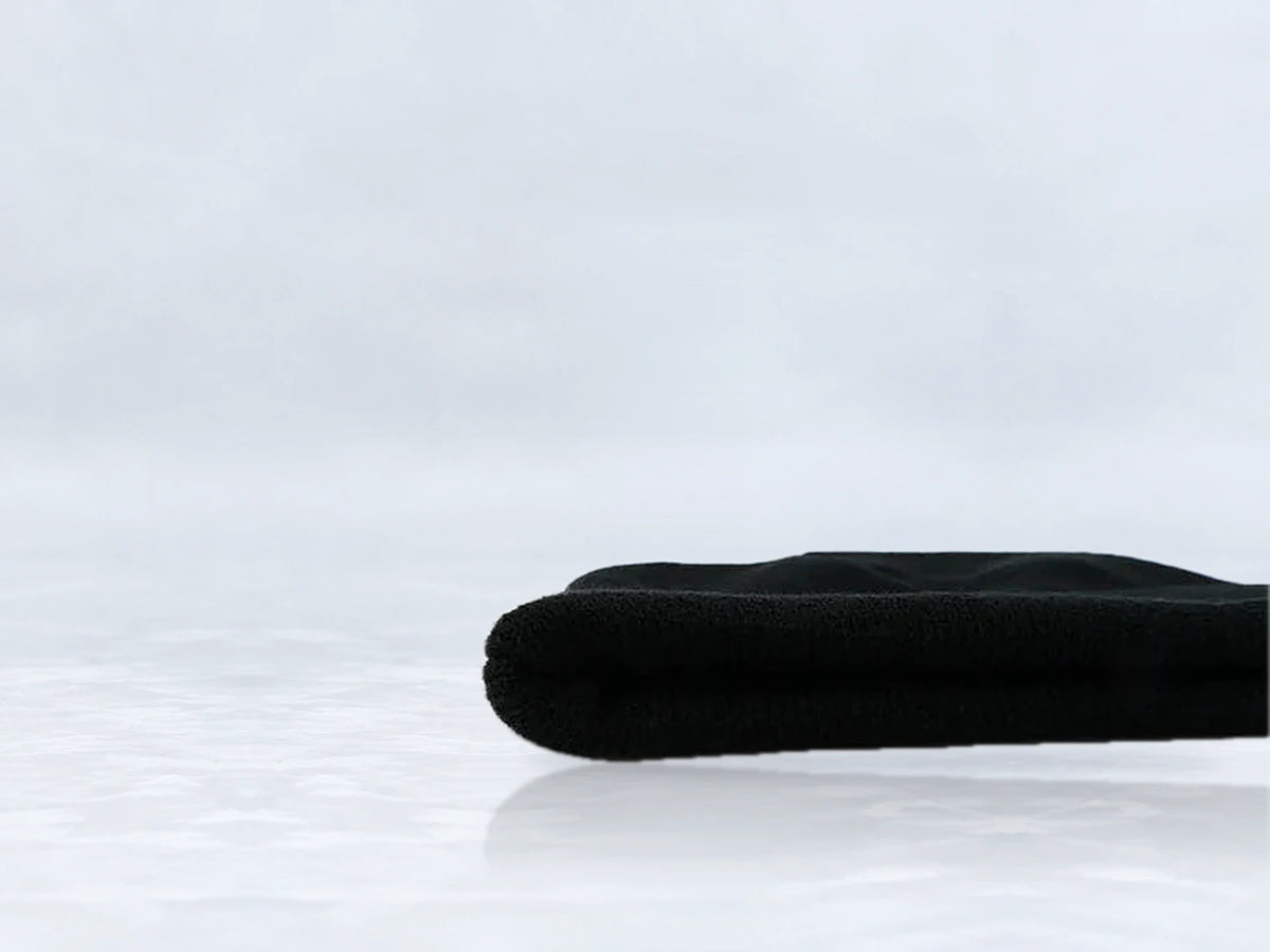 All In Lid Jet Black cuffed beanie in black knit, side view of the folded cuff, against a pale gray studio background.