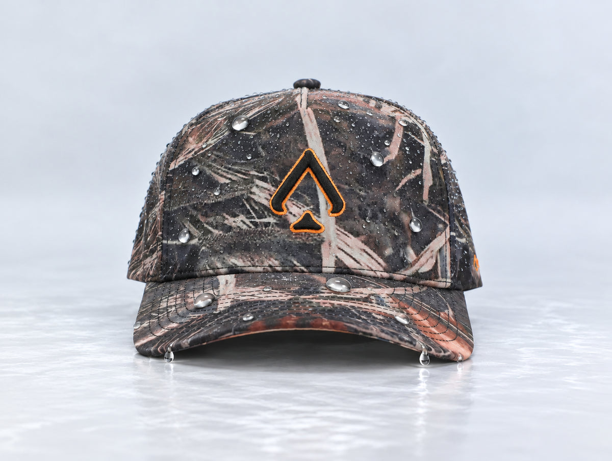 Front view of the All In Lid Killa Camo hat with woodland camouflage and an orange-outlined black logo and water droplets on the crown and brim.