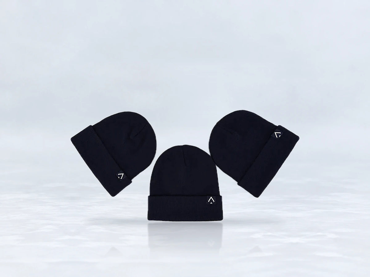 All In Lid Midnight Navy cuffed beanie in navy knit with a white logo patch, flat lay of three beanies, against a pale gray studio background.