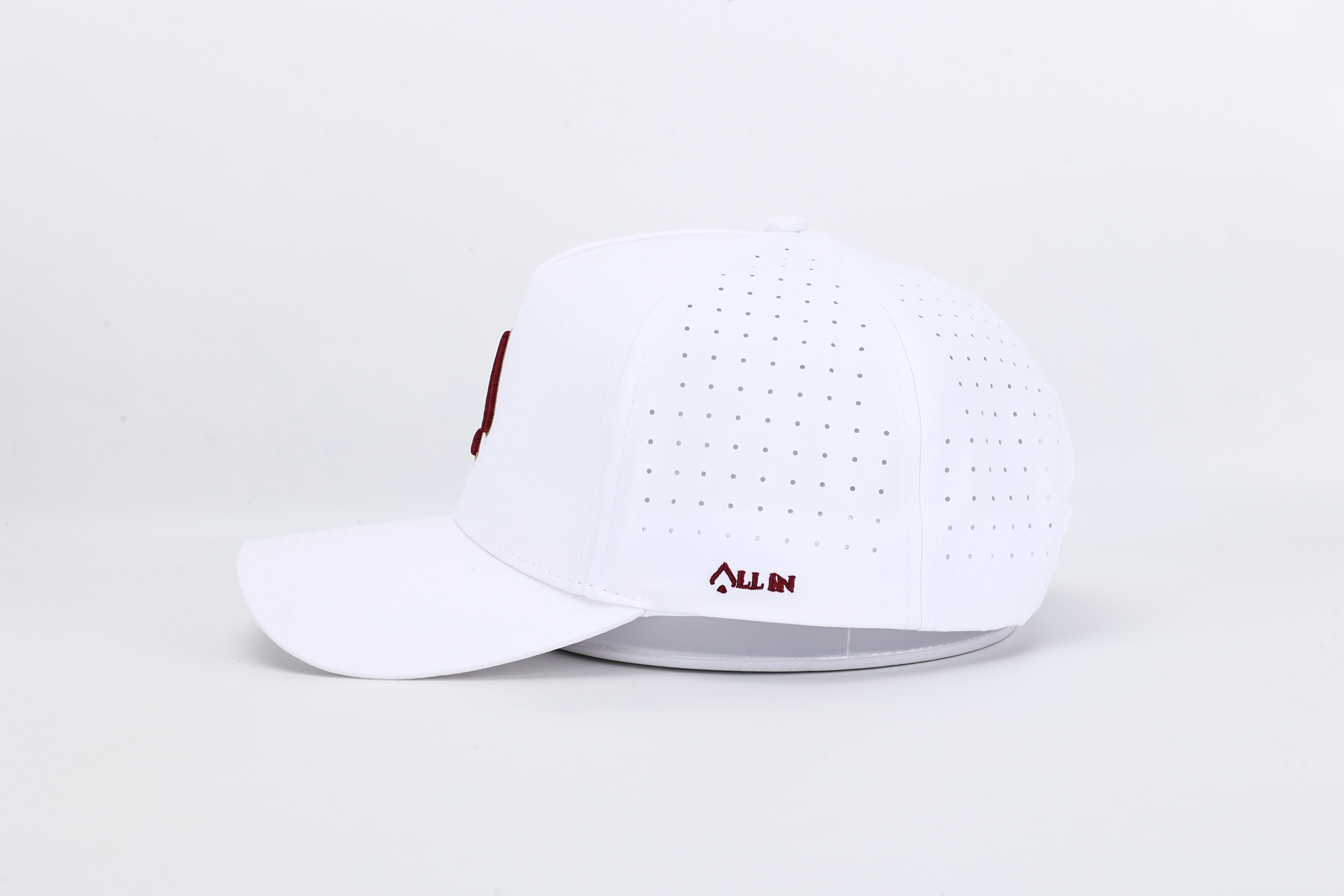 All In Wears Regal White performance cap, featuring a white body and an embroidered garnet and gold outline spade logo.