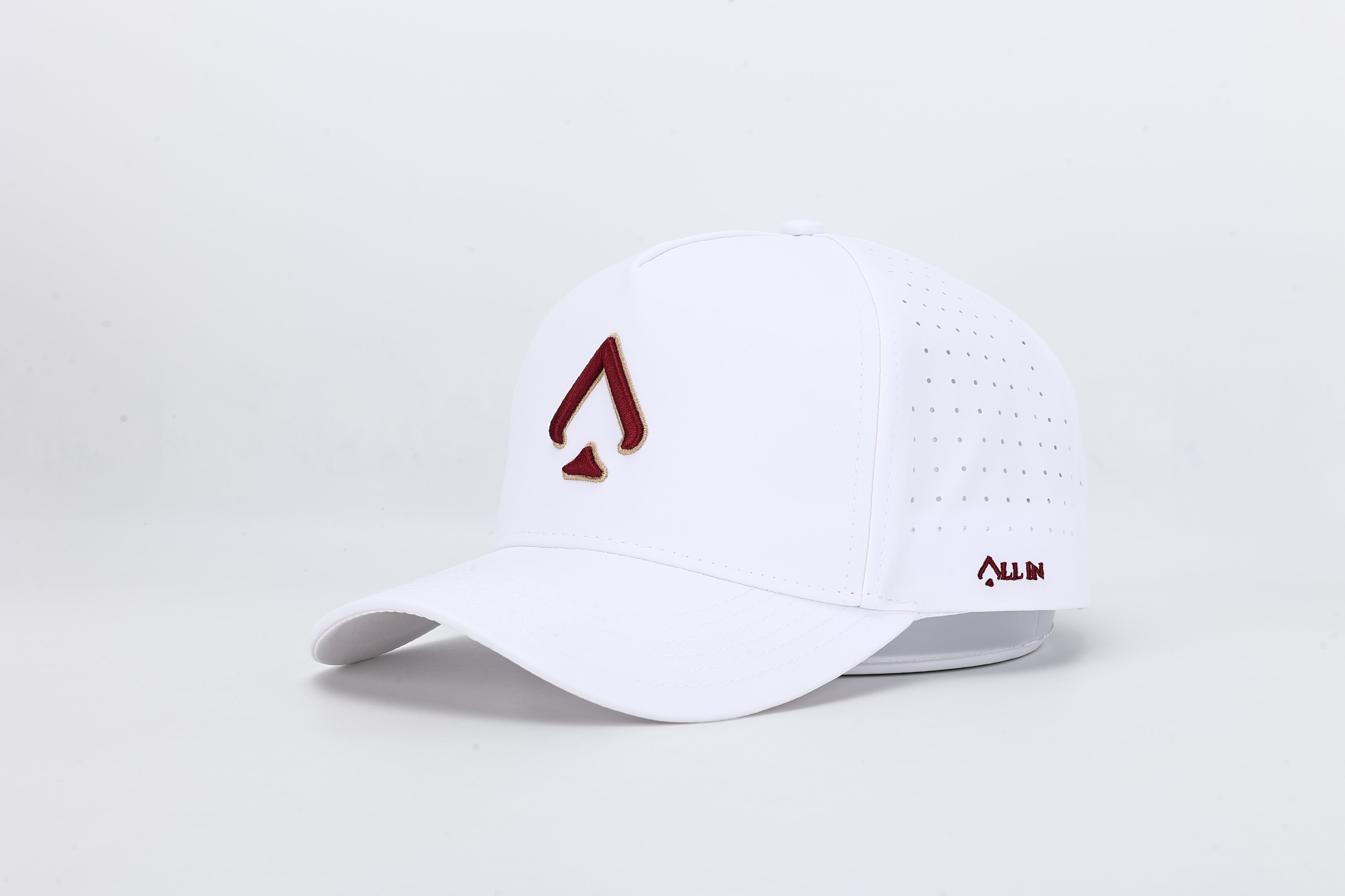 All In Wears Regal White performance cap, featuring a white body and an embroidered garnet and gold outline spade logo.