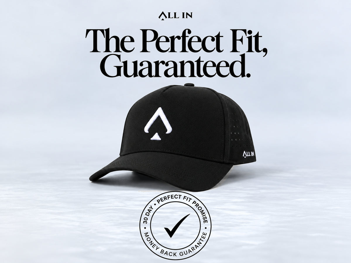 A black baseball cap with a white spade logo on the front and a small white ALL IN logo on the side, shown against a light gray background with large text reading 'The Perfect Fit, Guaranteed.' and a circular fit guarantee badge below.