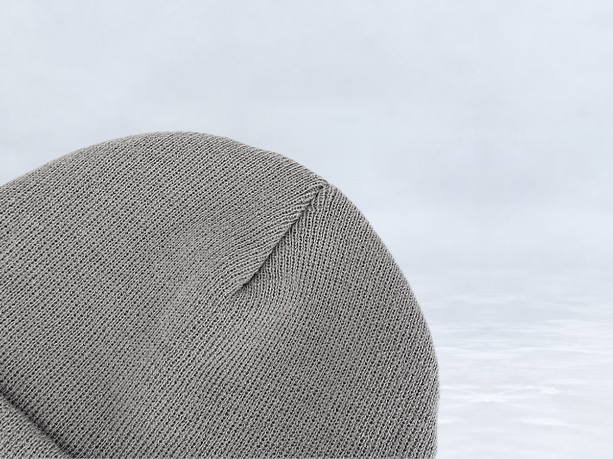 All In Lid Ash Gray cuffed beanie in gray knit, close-up of the knit crown, against a pale gray studio background.