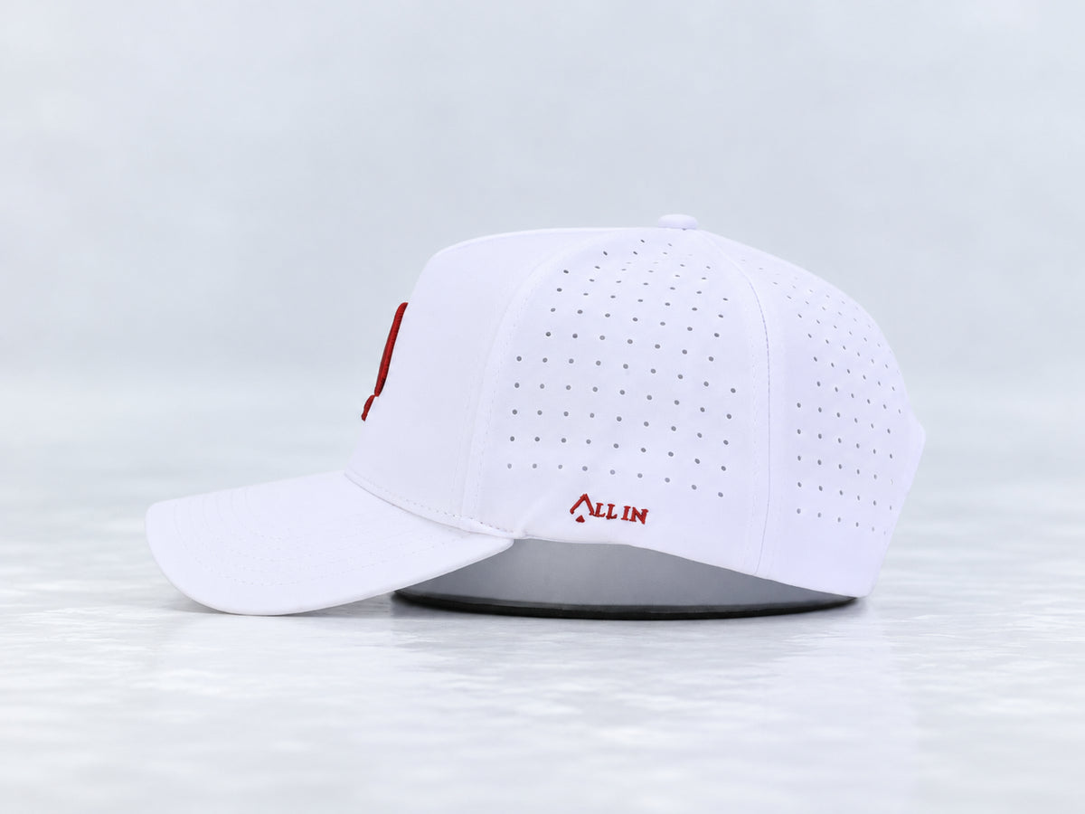 All In Lid Crimson Ice white cap, side view with crimson red All In embroidery, perforated panels, and a curved brim against a pale gray background.