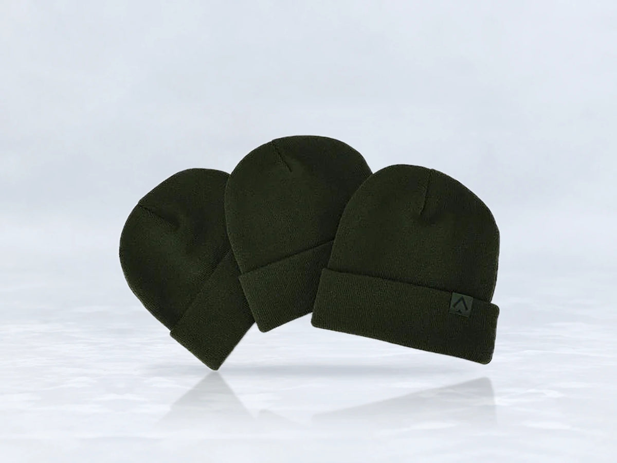 All In Lid Forest Green cuffed beanie in forest green knit with a tonal green logo patch, three beanies stacked, against a pale gray studio background.