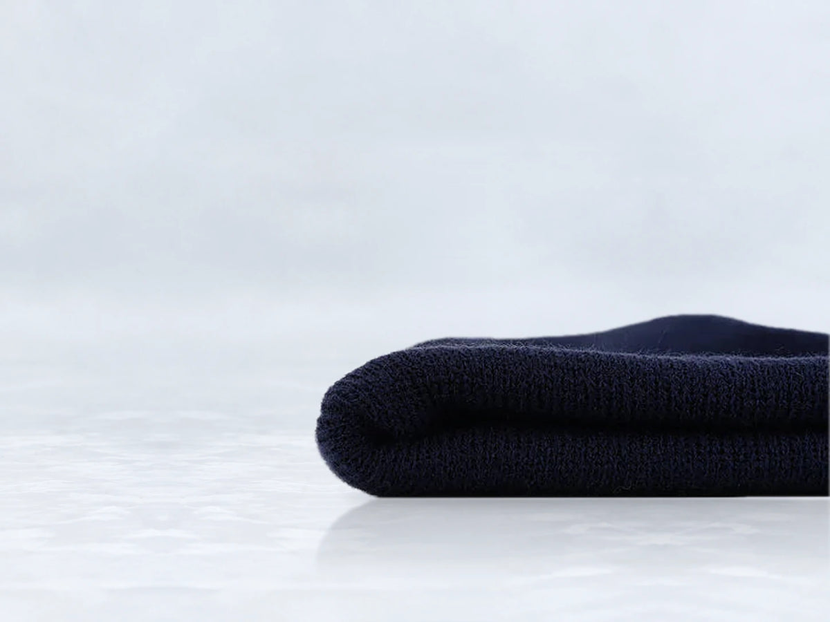 All In Lid Midnight Navy cuffed beanie in navy knit, side view of the folded cuff, against a pale gray studio background.