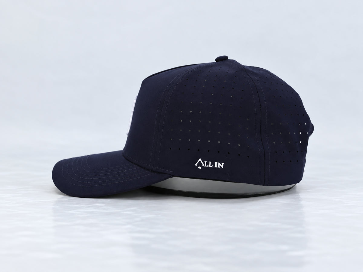 All In Lid Navy Seal navy cap, side view with white All In embroidery, perforated panels, and a curved brim against a pale gray background.
