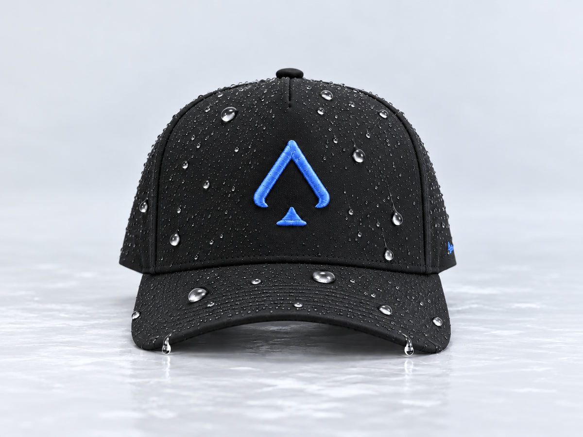 All In Lid Royal Blue black cap with royal blue spade embroidery and beaded water droplets on the crown and brim, straight-on front view against a pale gray background.