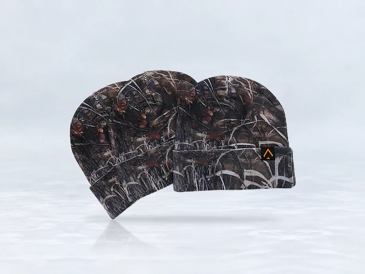All In Lid Stealth Camo cuffed beanie in woodland camo knit with an orange-outlined logo patch, three beanies stacked, against a pale gray studio background.