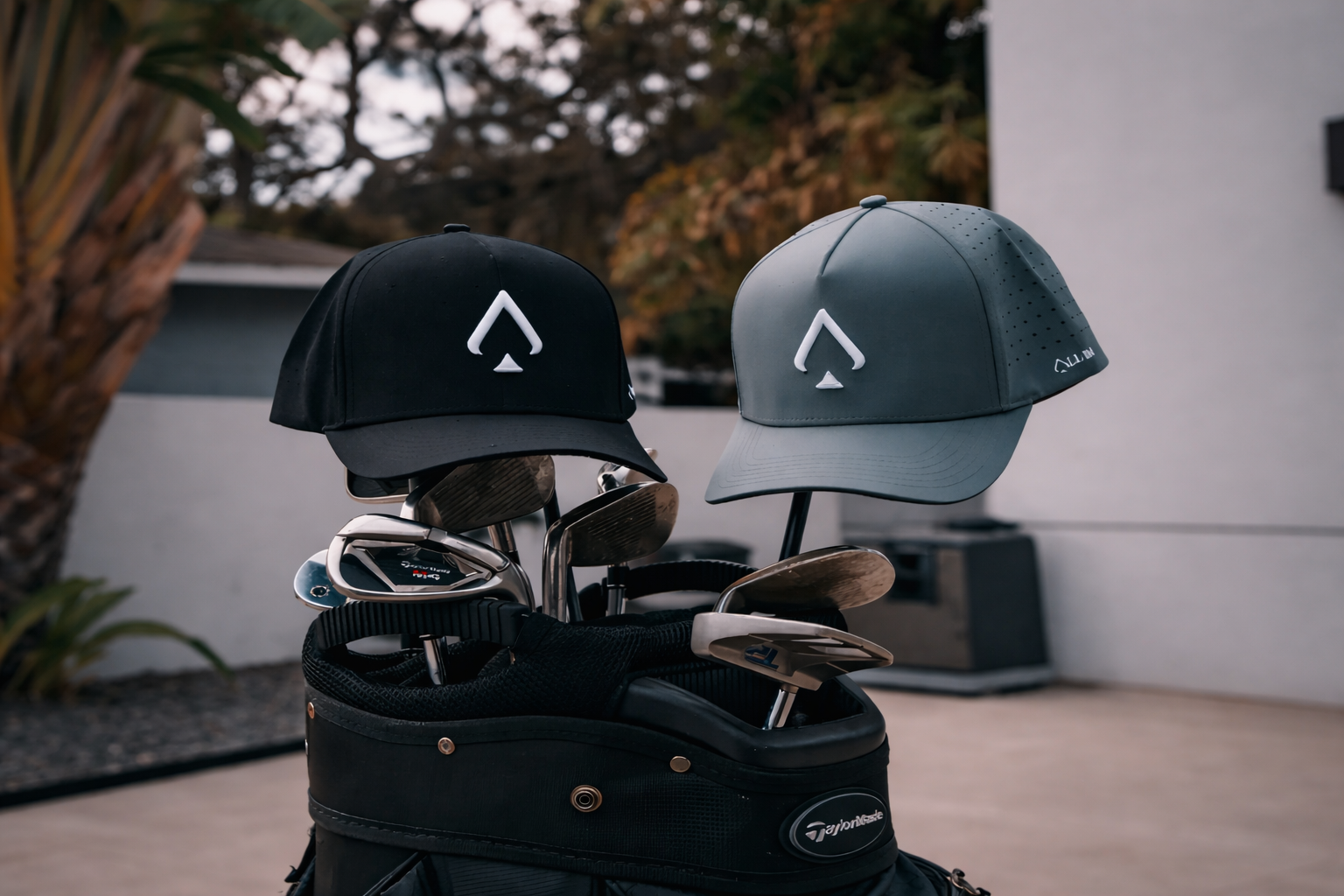 Two golf hats with a logo on top of a golf bag with golf clubs.